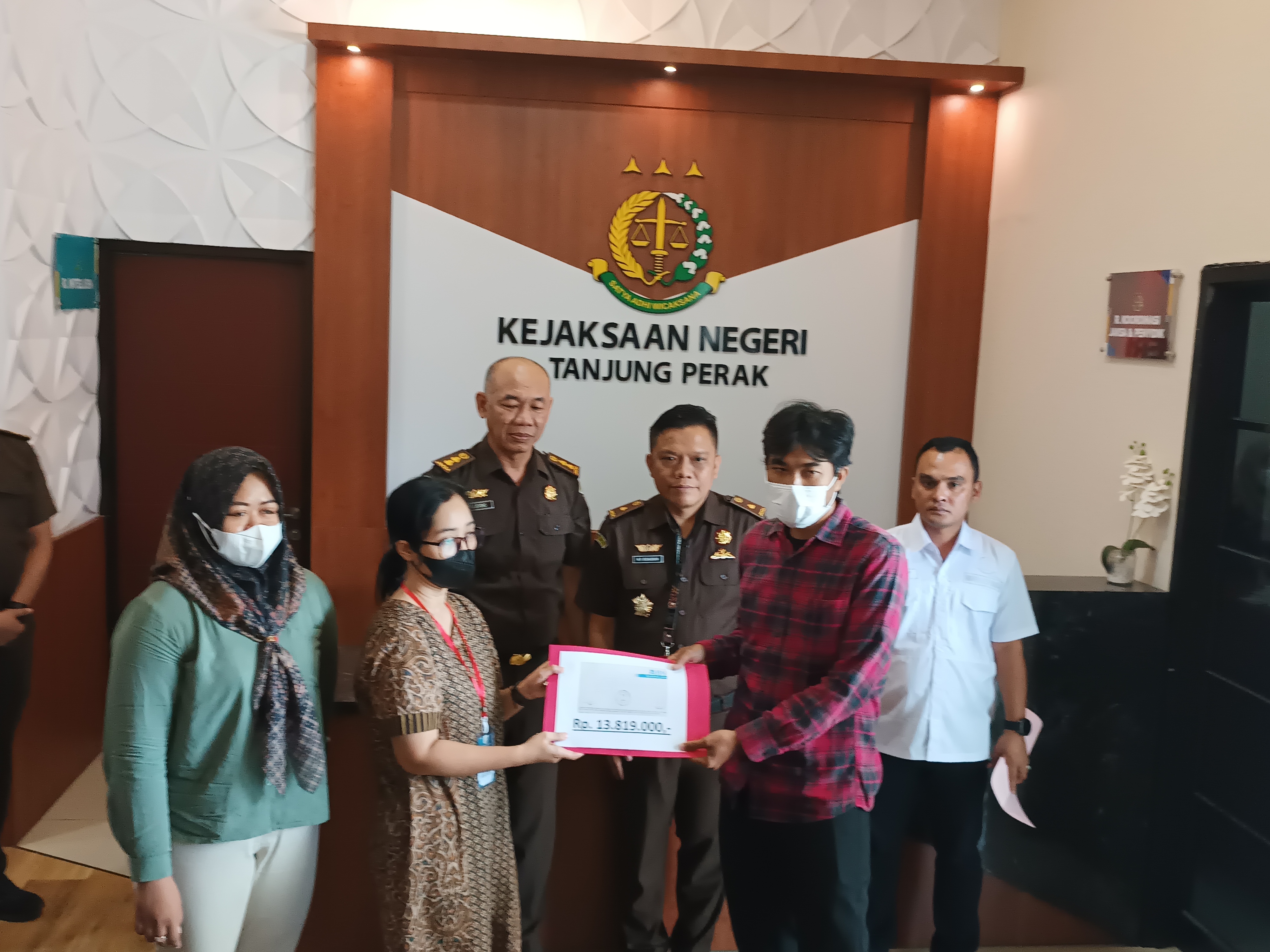 Nurhadi (kemeja merah) saat menerima restitusi atau ganti rugi dari keluarga polisi terpidana kekerasan. (Dok: Jurnas.net)