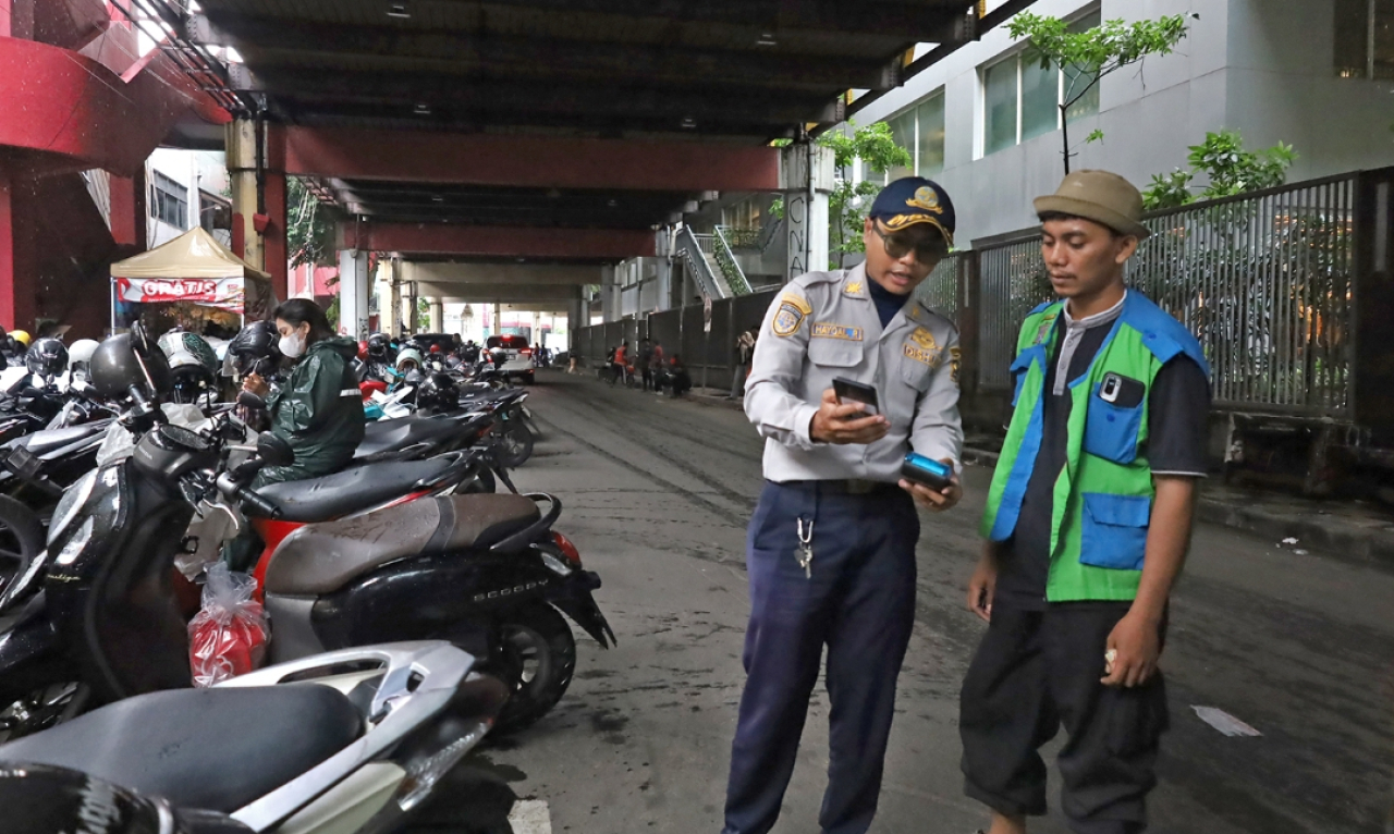 Petugas Dishub Surabaya menunjukkan kepada jukir terkait parkir sistem digital non tunai. (Humas Pemkot Surabaya)