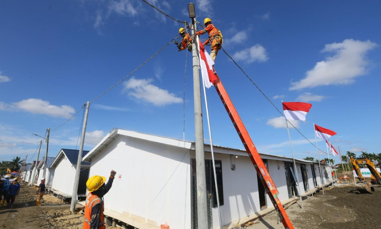 Petugas PLN menyambung jaringan listrik di hunian sementara Aceh. (Humas BKP RI)