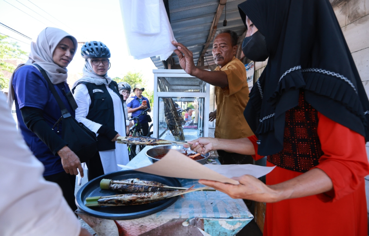 Bupati Banyuwangi, Ipuk Fiestiandani, membeli ikan asap Pantai Blimbingsari di Kecamatan Blimbingsari, Kabupaten Banyuwangi. (Humas Pemkab Banyuwangi)